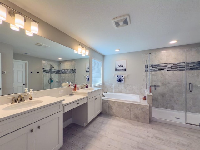 bathroom with a garden tub, a sink, a shower stall, and double vanity