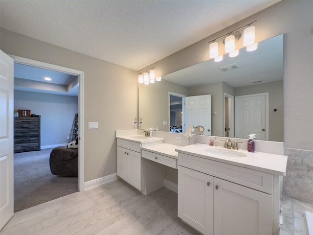 bathroom featuring visible vents, connected bathroom, vanity, wood finished floors, and baseboards