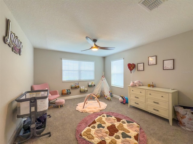 rec room featuring light colored carpet, ceiling fan, visible vents, and a textured ceiling