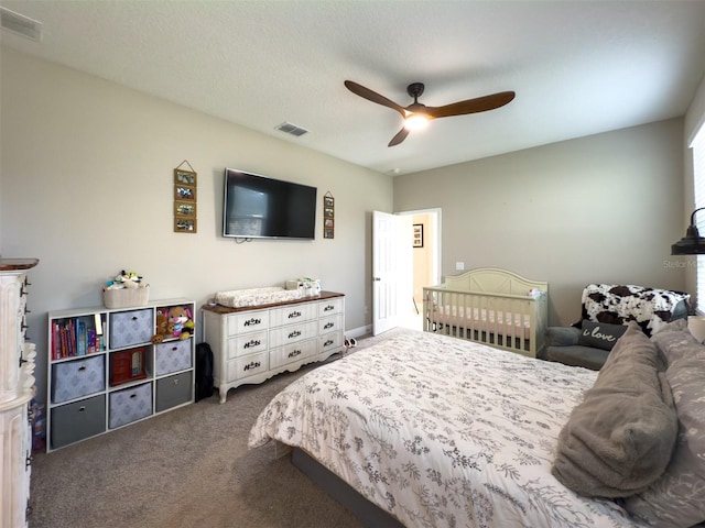bedroom featuring a ceiling fan, dark colored carpet, visible vents, and a textured ceiling