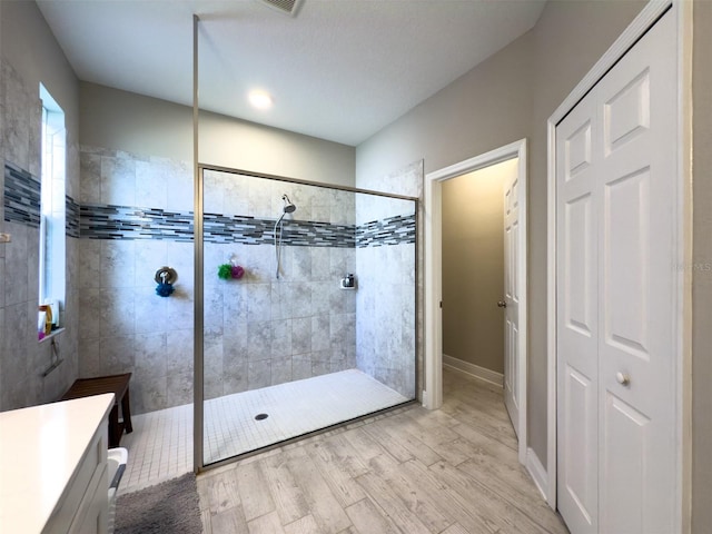 full bath with baseboards, wood finished floors, walk in shower, vanity, and a closet