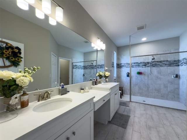 full bathroom with double vanity, visible vents, a sink, and a walk in shower