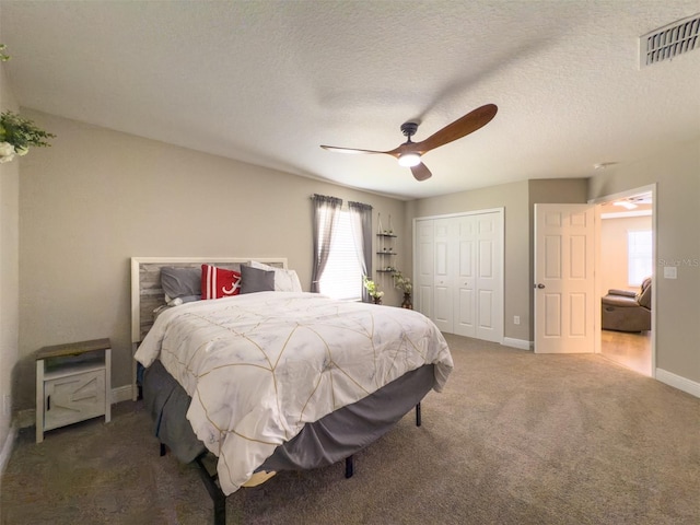 bedroom with baseboards, visible vents, a textured ceiling, dark carpet, and a closet