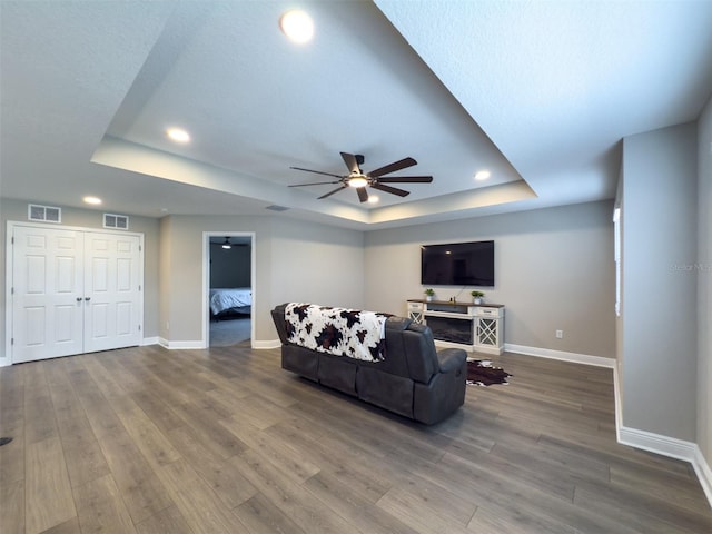 living area featuring visible vents, a tray ceiling, and wood finished floors