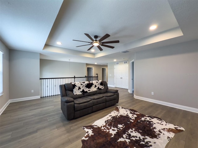 living room with a raised ceiling, baseboards, and wood finished floors