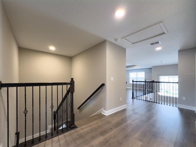 interior space with baseboards, visible vents, wood finished floors, and an upstairs landing