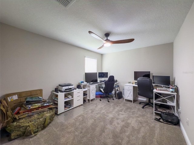 carpeted home office featuring baseboards, ceiling fan, visible vents, and a textured ceiling
