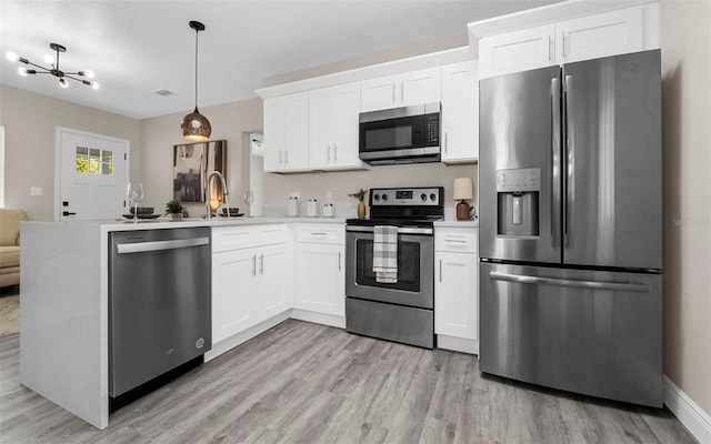 kitchen featuring decorative light fixtures, light countertops, white cabinets, and stainless steel appliances