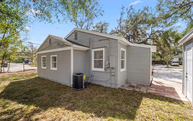 view of property exterior featuring fence, central AC, and a yard