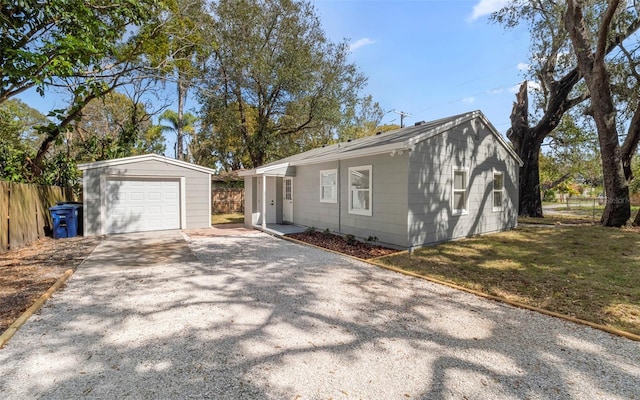 view of front of home featuring fence, an outbuilding, a front lawn, driveway, and a garage