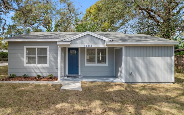 ranch-style home featuring roof with shingles and a front yard