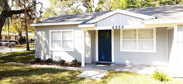 entrance to property featuring roof with shingles