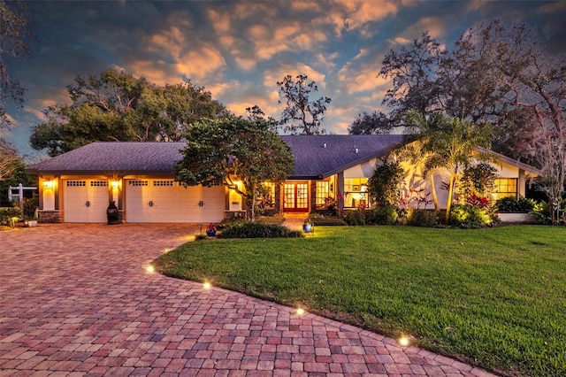 view of front of property featuring decorative driveway, a yard, and an attached garage