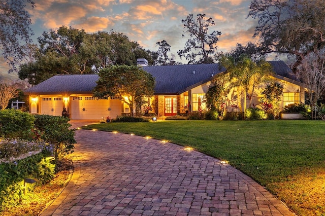 view of front of house featuring a garage, a front yard, decorative driveway, and a chimney