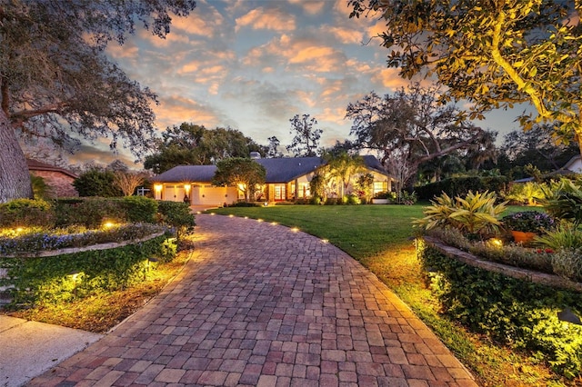 view of front of home with an attached garage, decorative driveway, and a front yard