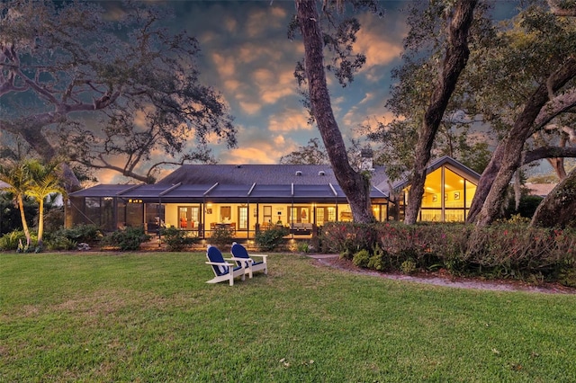 rear view of property featuring a lanai and a lawn