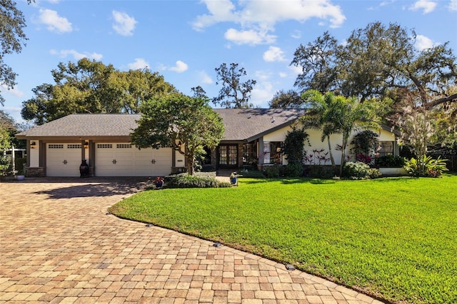 ranch-style house with a garage, a front lawn, and decorative driveway