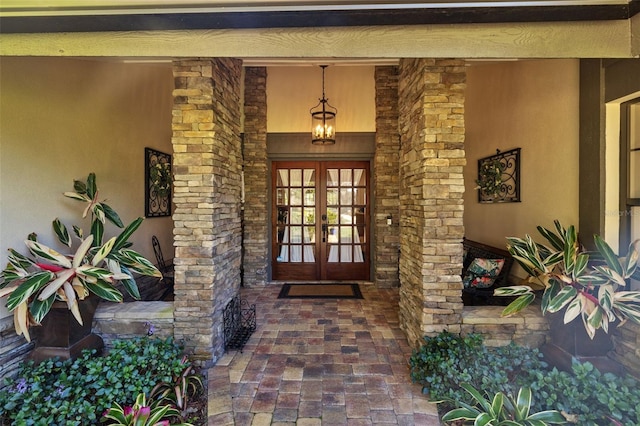 entrance to property with stone siding, french doors, and stucco siding