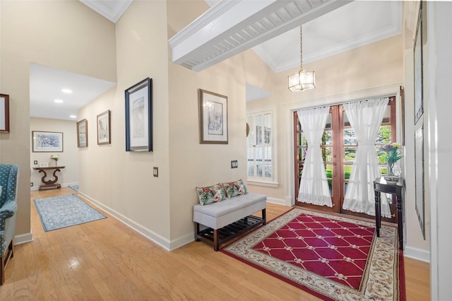 entrance foyer featuring ornamental molding, a towering ceiling, baseboards, and wood finished floors