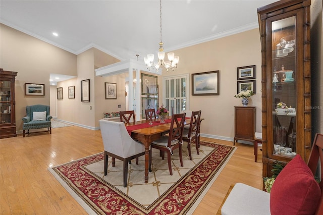 dining area featuring crown molding, baseboards, a notable chandelier, and light wood-style floors