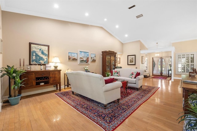 living room with light wood-type flooring, high vaulted ceiling, visible vents, and ornamental molding