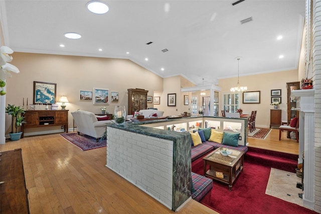 living room with lofted ceiling, ornamental molding, wood-type flooring, and visible vents