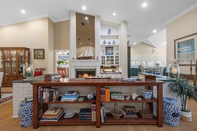 interior space with a lit fireplace, ornamental molding, and wood finished floors