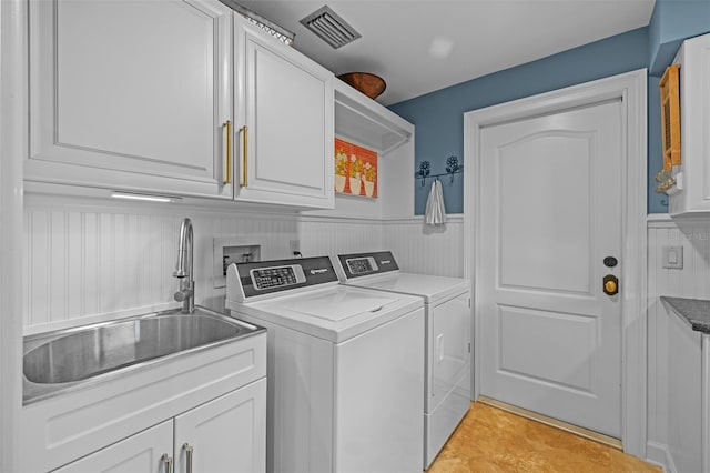 washroom featuring cabinet space, visible vents, wainscoting, a sink, and independent washer and dryer