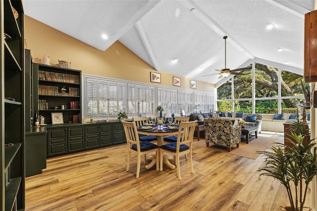 dining area featuring lofted ceiling with beams, light wood-style floors, ceiling fan, and a textured ceiling