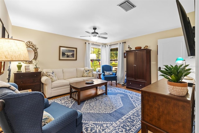 living room with ceiling fan, dark wood finished floors, and visible vents