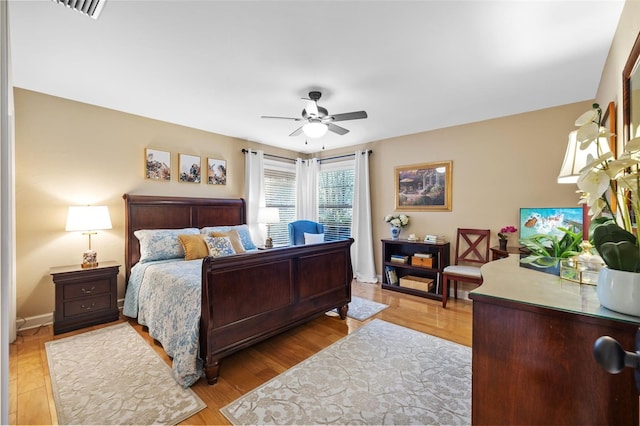 bedroom with a ceiling fan, visible vents, light wood-style flooring, and baseboards