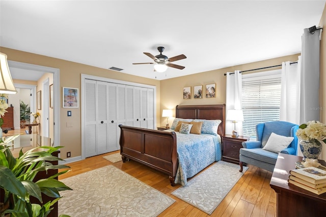 bedroom with light wood-style floors, a closet, visible vents, and ceiling fan