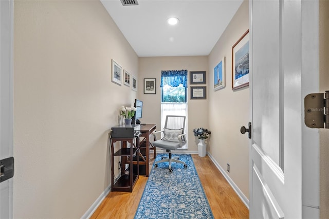 office with light wood-type flooring, visible vents, and baseboards