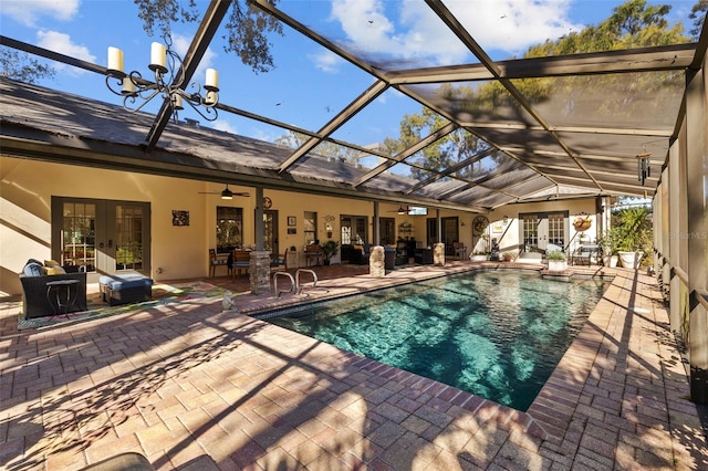 pool with glass enclosure, outdoor lounge area, a ceiling fan, french doors, and a patio area