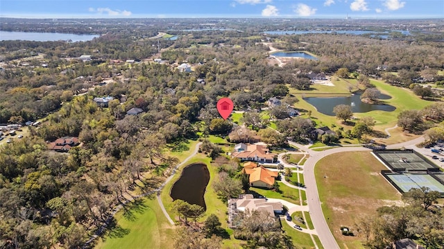 drone / aerial view featuring a water view, a wooded view, and golf course view