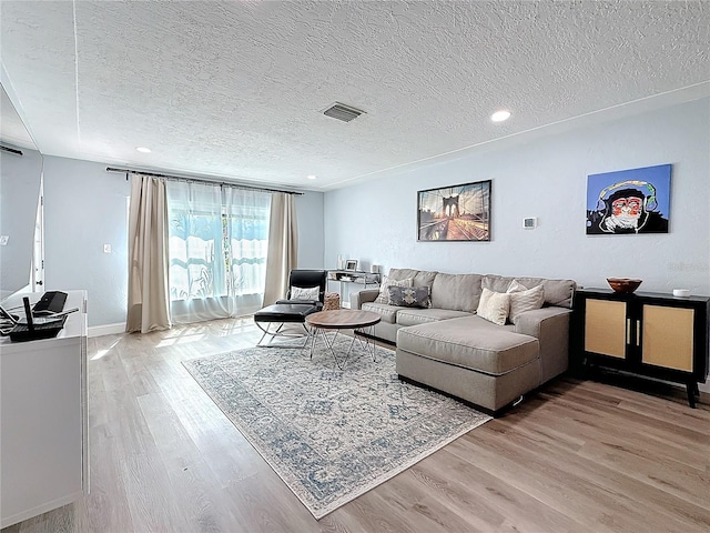 living room with light wood-type flooring and a textured ceiling