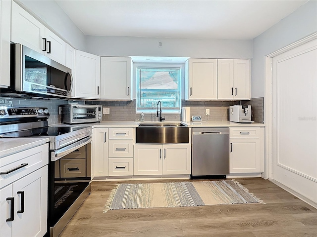 kitchen with appliances with stainless steel finishes, sink, and white cabinets