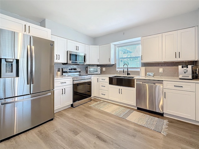 kitchen with light hardwood / wood-style flooring, sink, stainless steel appliances, and white cabinetry