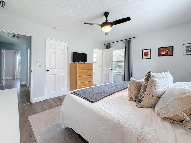 bedroom with ceiling fan, wood-type flooring, and a textured ceiling