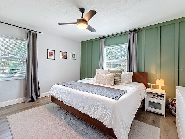 bedroom with ceiling fan, light hardwood / wood-style floors, and a textured ceiling