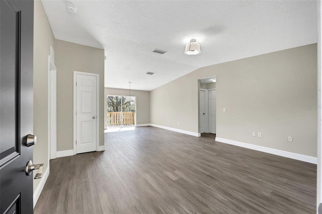 spare room with dark wood finished floors, lofted ceiling, visible vents, and baseboards