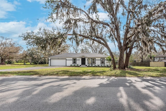 view of front of property featuring a garage, driveway, a front yard, and fence