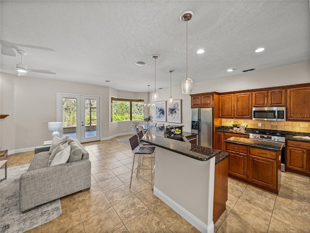 kitchen featuring sink, a center island with sink, appliances with stainless steel finishes, and pendant lighting