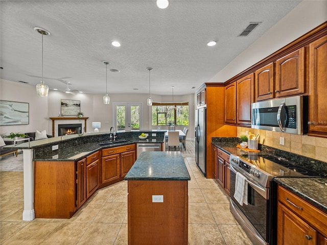 kitchen with sink, backsplash, a center island, decorative light fixtures, and stainless steel appliances