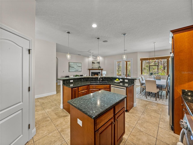 kitchen featuring an island with sink, dark stone countertops, sink, and pendant lighting