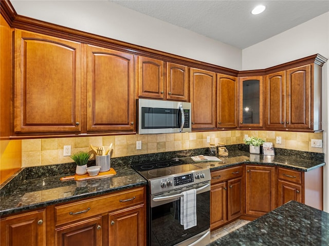 kitchen featuring appliances with stainless steel finishes, dark stone countertops, and decorative backsplash