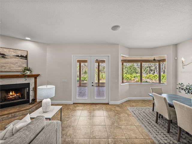 tiled living room with a textured ceiling, a premium fireplace, french doors, and a wealth of natural light