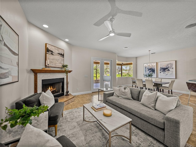 living room featuring a fireplace, ceiling fan, french doors, and a textured ceiling