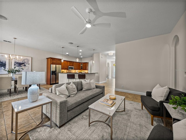 living room featuring ceiling fan with notable chandelier and light tile patterned floors