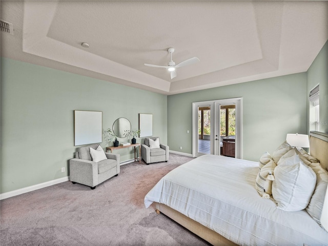 carpeted bedroom with access to exterior, french doors, ceiling fan, and a raised ceiling